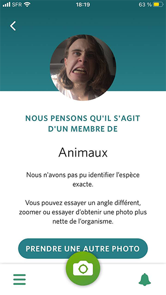 Une capture d'écran du jeu mobile Seek by iNaturalist. On y voit une photo d'humain faisant une grimace, avec une légende indiquant Nous pensons qu'il s'agit d'un membre des Animaux, nous n'avons pas pu identifier l'espèce exacte .